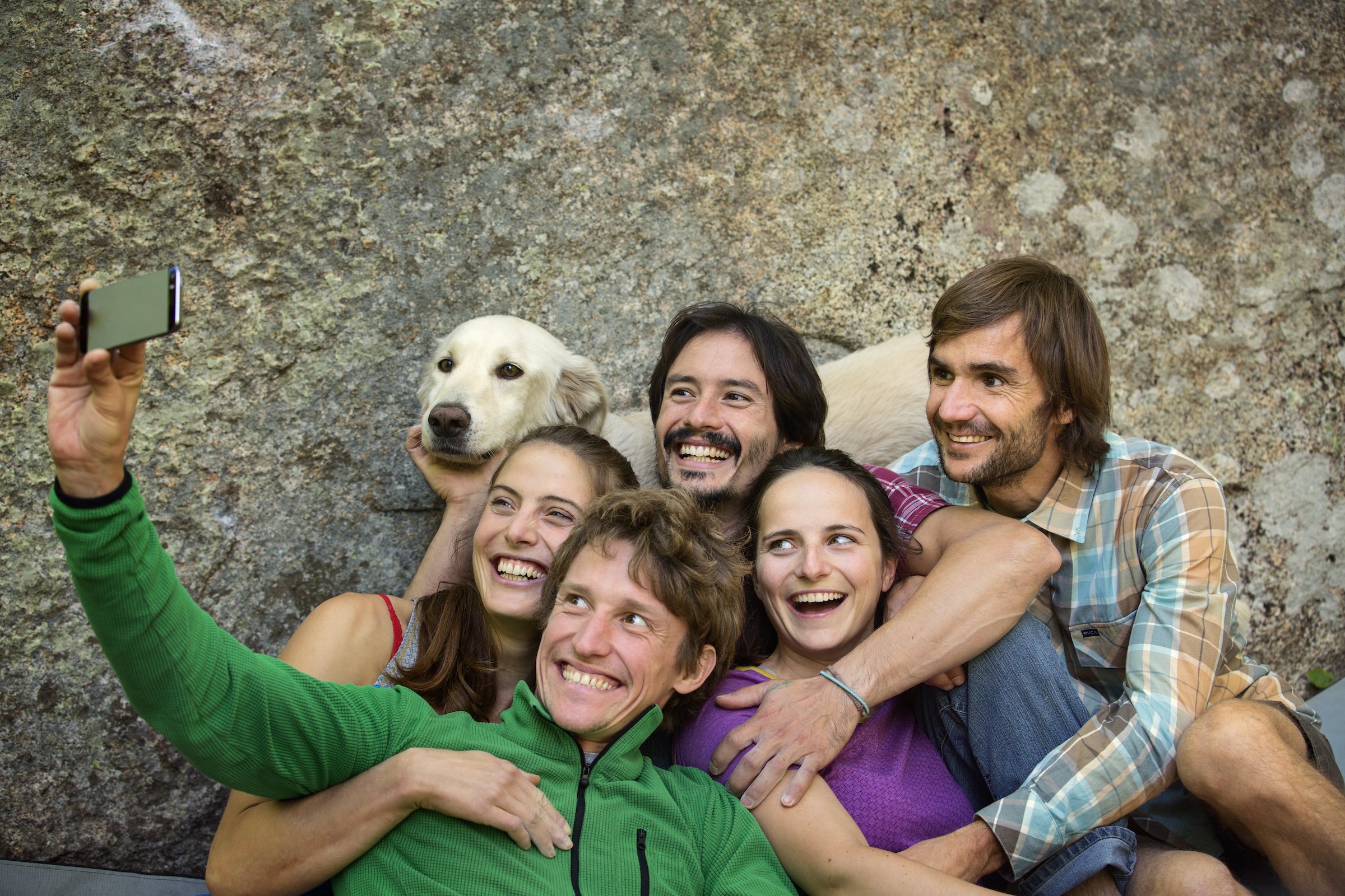 Friends taking selfie with dog against rock