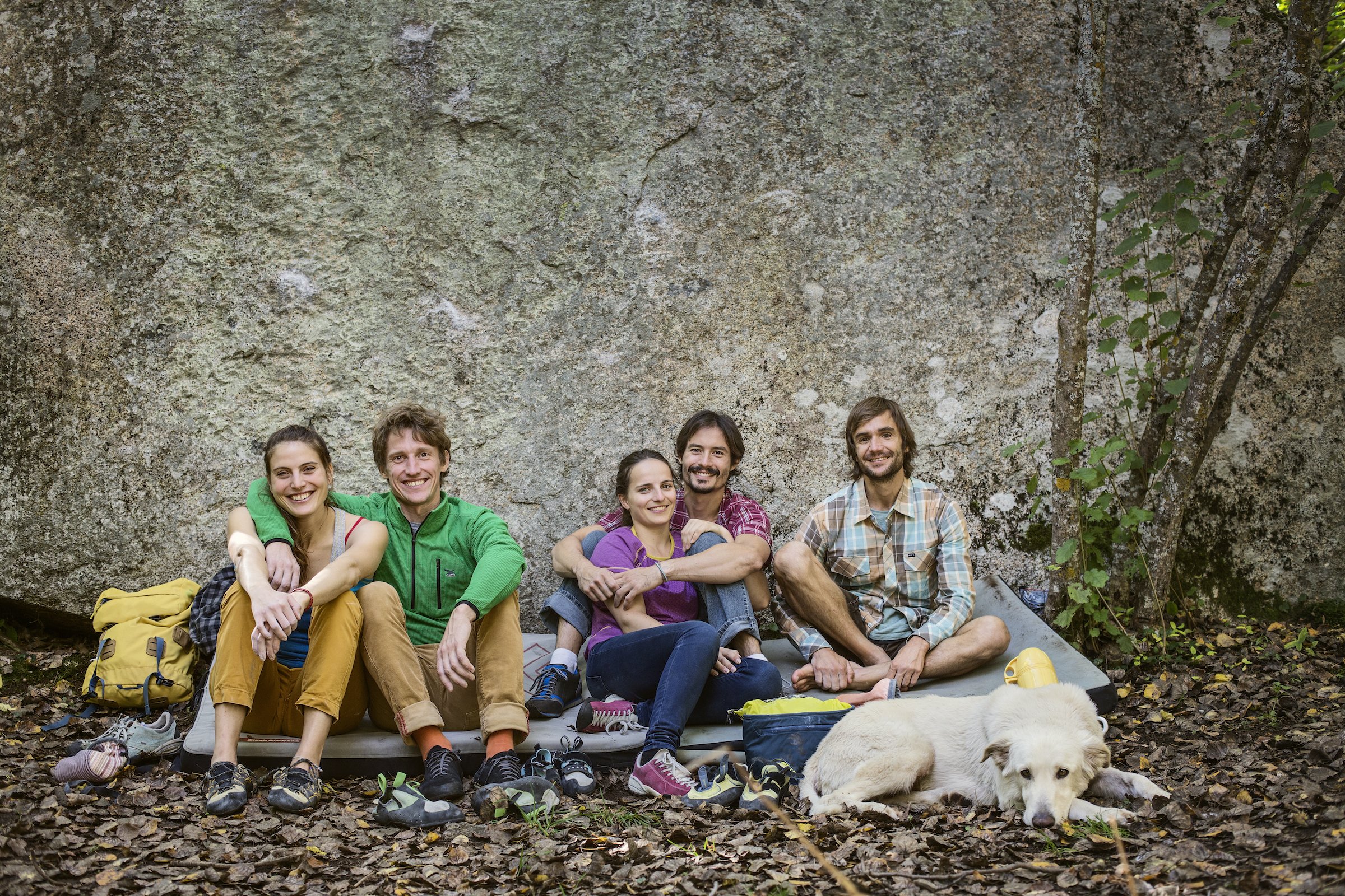 Friends with dog relaxing against rock