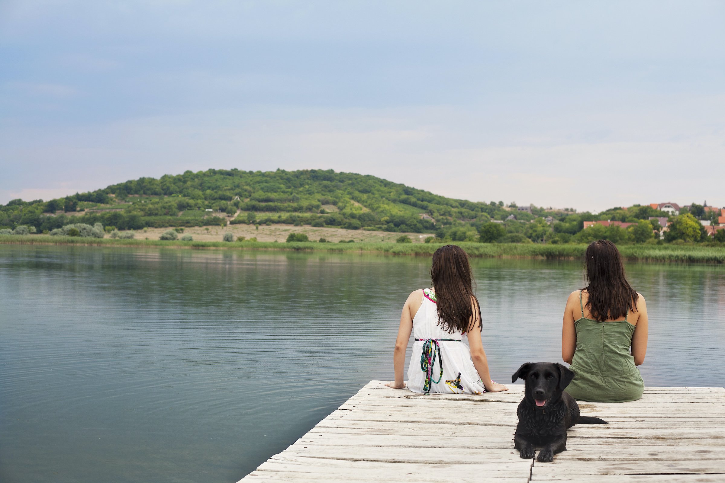 Women sitting with dog on pier