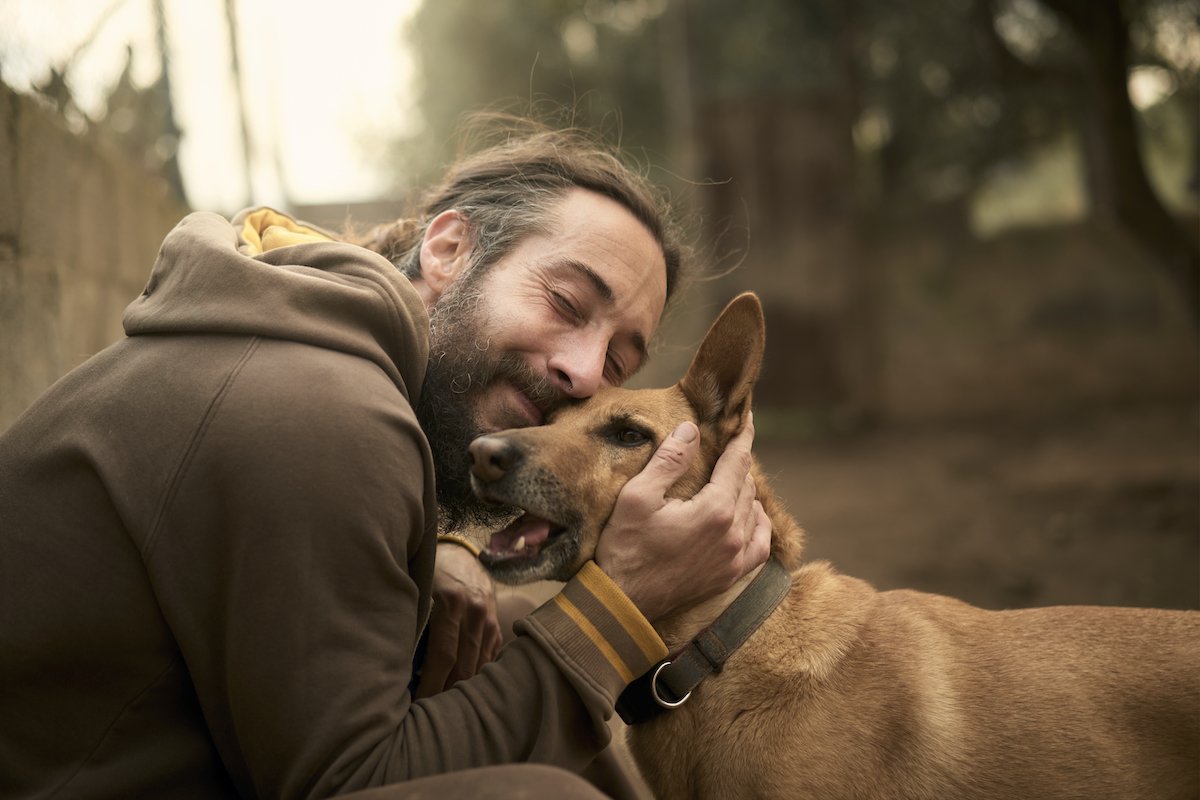 Young bearded adult man hugging his dog