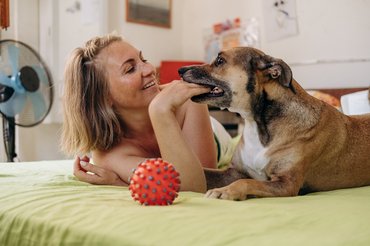 Egy nő és egy kutya labdával játszik