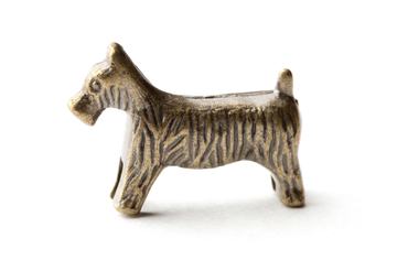 Belen, New Mexico, USA - May 23, 2011: A small metal token in the shape of a Scottie dog for use in the game Monopoly. Monopoly is a property trading game published by Parker Brothers, a subsidiary of Hasbro.