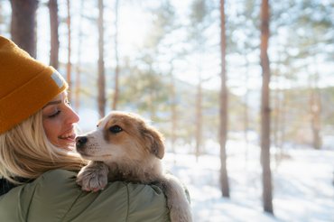 egy nő kutyájával havas tájon