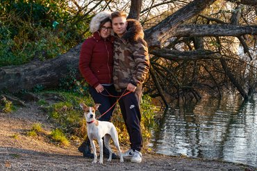 fiatal pár tóparton sétáltatja a kutyáját