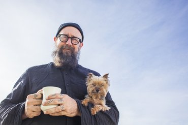 idősebb szakállas férfi yorkshire terrierrel a karjában