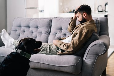 kanapén ülő férfi kutyával